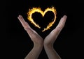 hands with heart fire icon over. Black background Royalty Free Stock Photo