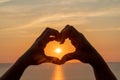 Hands heart sea sanset. Hands forming a heart shape made against the sun sky of a sunrise or sunset on a beach Royalty Free Stock Photo