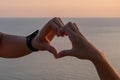 Hands heart sea sanset. Hands forming a heart shape made against the sun sky of a sunrise or sunset on a beach Royalty Free Stock Photo