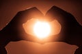 Hands in heart shape holding sun circle inside