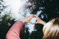 Hands in heart shape. One girl hands heart shape on against blurry forest background of summer or spring.Closeup