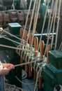 Hands help tie lines from sails on a tall ship