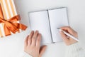 Hands hold an blank notebook among gift box. Flat lay. Royalty Free Stock Photo