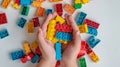 The Hands of the kids hold colorful toy bricks and blocks for building toys on a white background. Generative AI Royalty Free Stock Photo