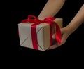 Hands hold gift box with red ribbon, copy space isolated on black. Sales concepts, discount price, christmas gifts Royalty Free Stock Photo