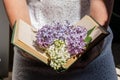 Hands hold an open book on which lies a branch of lilac, lilac flowers on the volume, a spring flower on an open book Royalty Free Stock Photo