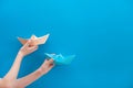 Hands that hold paper boats on a blue background. Traffic directions in business. Choosing the right development road. Travel and