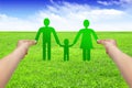 Hands hold paper family on grass, eco concept