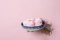 Hands hold a plate with homemade pink marshmallows through a torn hole on a pink paper background. Bakery advertising concept, rec