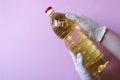 Hands hold pure sunflower oil in plastic bottle. Seasoning for salads. On pink background. Royalty Free Stock Photo