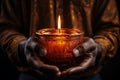 Hands hold a radiant candle, piercing through the darkened surroundings