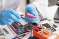 Hands hold a red lithium titanium battery and a voltmeter