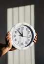 Hands hold round wall clock on background of shadow in form of prison lattice Royalty Free Stock Photo
