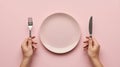 Hands holding fork and knife ready to eat above an empty pink plate on a pastel background Royalty Free Stock Photo