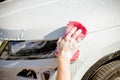 Male hand holding sponge for washing white car.dirty auto.Man worker washing windshield with sponge on a car wash.Manual car wash Royalty Free Stock Photo