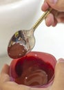 Hands hold a spoon and a bowl with red food coloring, which drip Royalty Free Stock Photo