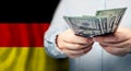 Hands holding American dollars banknote on German flag background Royalty Free Stock Photo