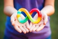 Hands holding Autism infinity rainbow symbol sign. World autism awareness day, autism rights movement, neurodiversity
