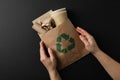 Hands holding bag with paper trash and recycle sign on black background Royalty Free Stock Photo