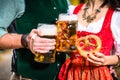 Hands holding Beer and Pretzels, detail of bavarian Tracht Royalty Free Stock Photo