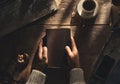 hands holding bible on old wood table with candle drink and old stuff top view