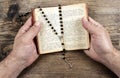 Hands holding the Bible and praying with a rosary Royalty Free Stock Photo