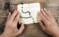 Hands holding the Bible and praying with a rosary Royalty Free Stock Photo