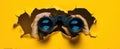 The Hands Holding Binoculars Peering Through a Torn Yellow Background.AI generated image Royalty Free Stock Photo