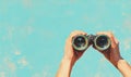 Hands holding binoculars on a textured blue background for exploration themes Royalty Free Stock Photo