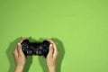 Hands holding a black joystick, game controller isolated on green background