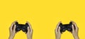 Hands holding a black joystick, game controller isolated on yellow background Royalty Free Stock Photo