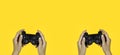 Hands holding a black joystick, game controller isolated on yellow background