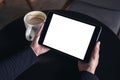 Hands holding black tablet pc with white blank screen and coffee cup on table background Royalty Free Stock Photo