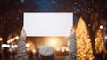 Hands holding blank banner in front of christmas tree at night