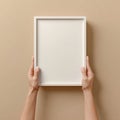 Hands Holding Blank White Picture Frame on Beige Background Royalty Free Stock Photo
