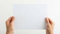 Hands holding a blank white piece of paper against a plain background Royalty Free Stock Photo