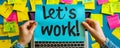 Hands holding a blue sticky note with the phrase lets work! amidst a chaotic background of colorful post-it notes and a Royalty Free Stock Photo