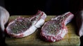 hands are holding a board on which are two raw pork steaks sprinkled with spices and ready to cook Royalty Free Stock Photo