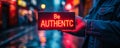 Hands holding a bold Be AUTHENTIC sign against a bokeh light background, promoting the value of authenticity and originality