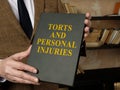 Hands holding a book Torts and Personal Injuries law book. Royalty Free Stock Photo