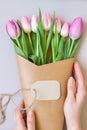 Hands holding bouquet of beautiful pink and purple fresh tulips with card Royalty Free Stock Photo