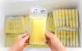 Hands holding Breast Milk Storage Bag in front of stocks in freezer Royalty Free Stock Photo