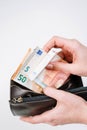 Hands holding brown leather wallet full of money - various Euros Eur banknotes.