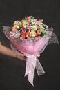 Florist holding a buquet of various flowers on the dark background