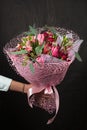 Florist holding a buquet of various flowers on the dark background