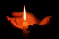Hands holding burning candle in dark. Concept of hope and warmth. Spirituality and prayer. Romantic flame of fire in female palms