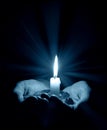 Hands holding a burning candle in dark room Royalty Free Stock Photo