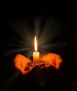 Hands holding a burning candle in dark room Royalty Free Stock Photo