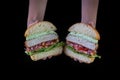 Hands holding a chicken burger with lettuce, tomato, purpple onion and handmade mayo on wood backgorund. Delicious Royalty Free Stock Photo