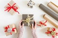 Hands holding a Christmas gift box, many small boxes wrapped in kraft paper and paper rolls